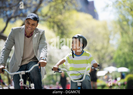 A family in the park on a sunny day. Father and son bicycling Stock Photo