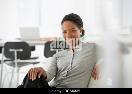 Business. A woman seated on the sofa looking relaxed. Stock Photo