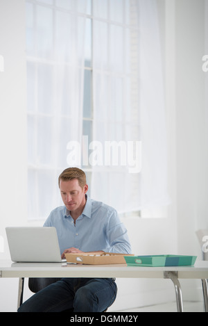 Business. A man sitting at a desk using a laptop. Stock Photo