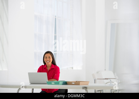 Asian businesswoman seated at desk using a laptop. Stock Photo