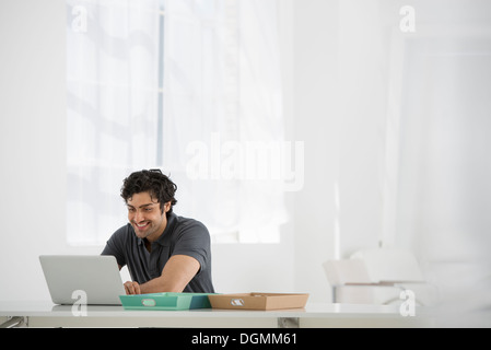 Business. A man sitting at a desk using a laptop. Stock Photo