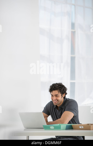 A man sitting at a desk using a laptop. Stock Photo