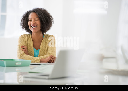 Business. A woman sitting at a desk. Digital tablet and laptop, and green files. Stock Photo