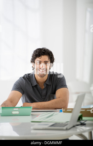 Business. A man sitting in a relaxed pose behind a desk. Stock Photo