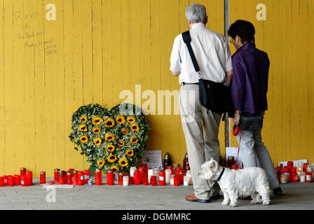 Older couple with dog walking past candles in memory of the victims, spot of the crowd crush at the Loveparade 2010, Duisburg Stock Photo