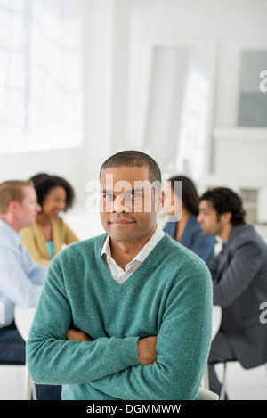 Business meeting. A group sitting down around a table. A man smiling confidently. Stock Photo