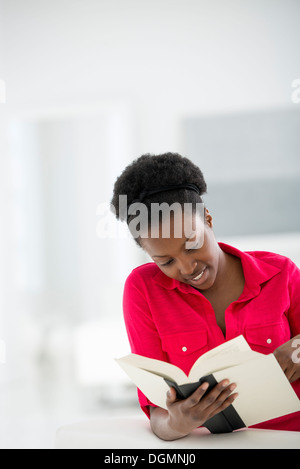 A bright white room interior. A woman sitting reading a book. Stock Photo