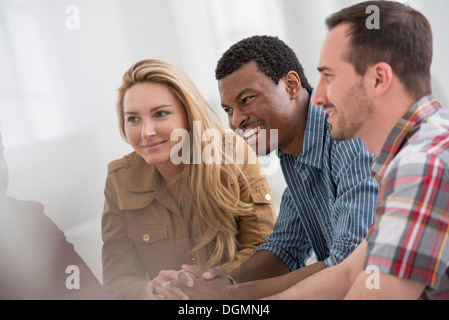Office. A group of four people, two men and two women seated talking. Stock Photo