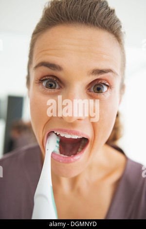 Funny portrait of young woman intensively brushing teeth Stock Photo
