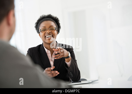 Office interior. A woman in a black suit jacket talking to a man. Stock Photo
