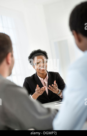 Office interior. Three people sitting around a table at a business meeting. Stock Photo