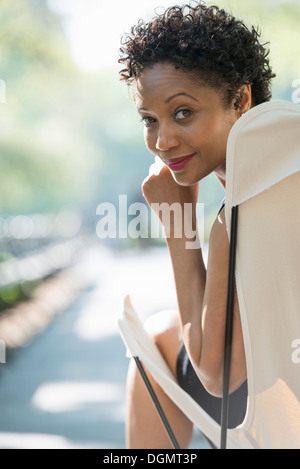 City life. A woman sitting in a camping chair in a park looking over her shoulder. Stock Photo