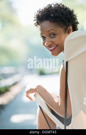 City life. A woman sitting in a camping chair in a park looking over her shoulder. Stock Photo