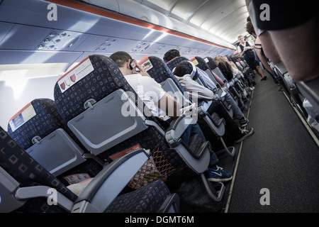 Onboard an EasyJet flight, bound for Spain, showing the flight attendant walking the aisle. Stock Photo