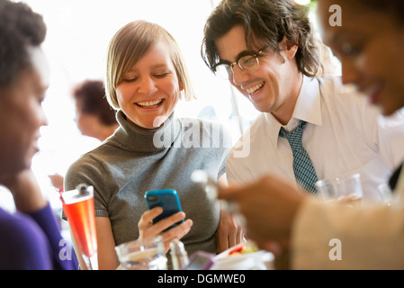 City life. A group of people in a café, checking their smart phones. Stock Photo