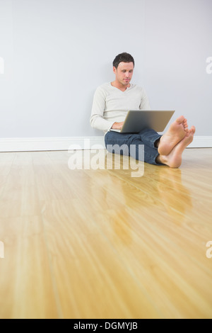 Casual attractive man leaning against wall using laptop Stock Photo