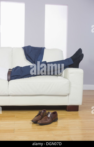 Close up of male legs in suit lying on couch Stock Photo