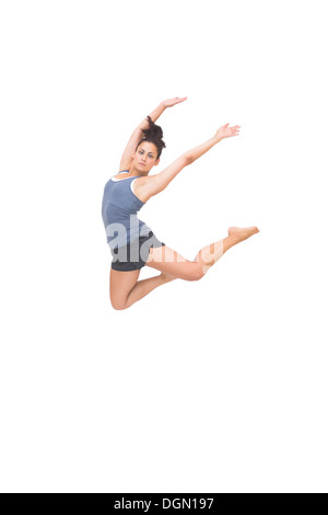 Pretty sporty brunette jumping in the air with arms up Stock Photo