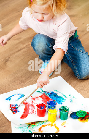 Cute little redhead girl painting with brush. Stock Photo
