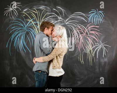 Studio portrait of young couple embracing in front of blackboard Stock Photo