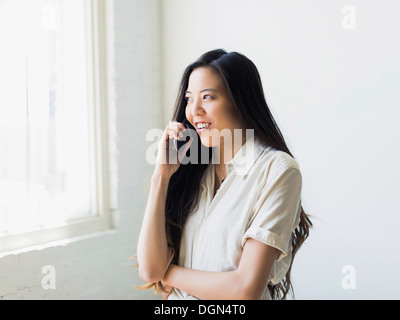 Smiling young woman talking via mobile phone Stock Photo