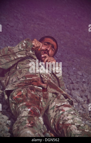 KHOWST PROVINCE, Afghanistan – A soldier with the Afghan National Army lies on the ground, simulating a casualty during a mass-casualty exercise on Camp Parsa, Afghanistan, Oct. 12, 2013. Stock Photo