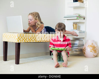 Kids (4-5, 6-7) using laptop and digital tablet indoors Stock Photo