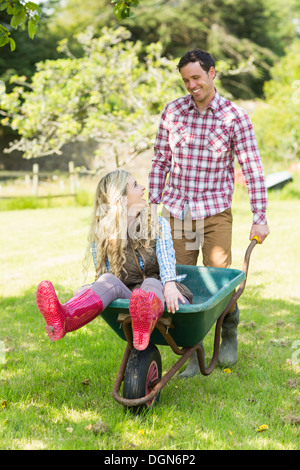 Happy man pushing his girlfriend in a wheelbarrow Stock Photo