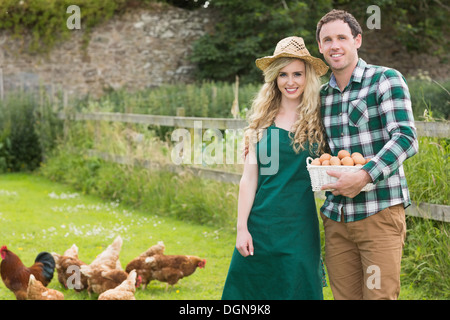 Young couple posing on a lawn holding a basket filled with eggs