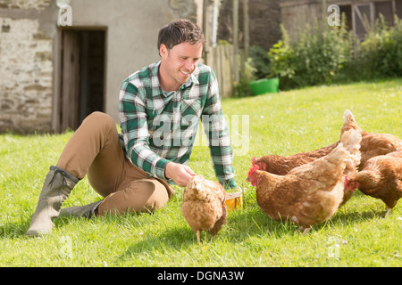 Young man feeding his chickens Stock Photo