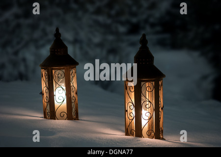 Candles burning in two lanterns on a snowy ground Stock Photo