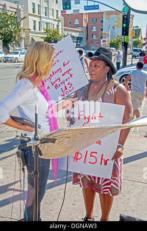 A television broadcast journalist interviews a participant in a demonstration of fast food workers in Los Angeles. Stock Photo