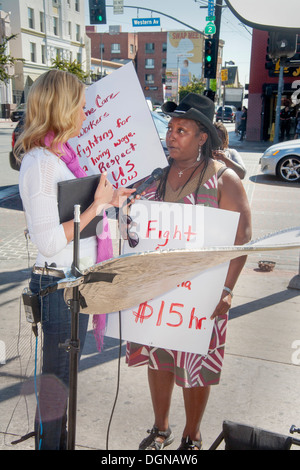 A television broadcast journalist interviews a participant in a demonstration of fast food workers in Los Angeles. Stock Photo