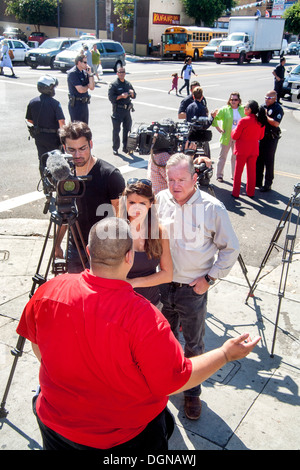 Broadcast journalist interviews Hispanic labor demonstration participant on Los Angeles street has her video cameraman records. Stock Photo