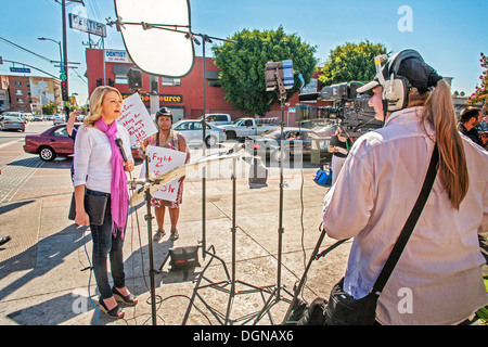 A television broadcast journalist interviews an African American woman participant in a demonstration of fast food workers in LA Stock Photo