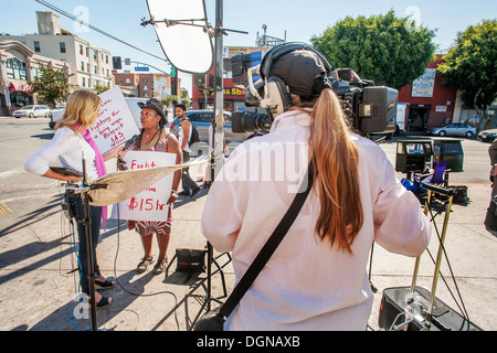 A television broadcast journalist interviews an African American woman participant in a demonstration of fast food workers in LA Stock Photo