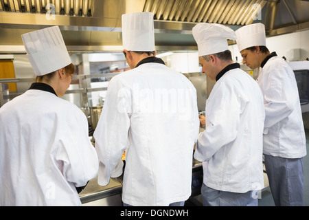 Four chefs working in industrial kitchen Stock Photo