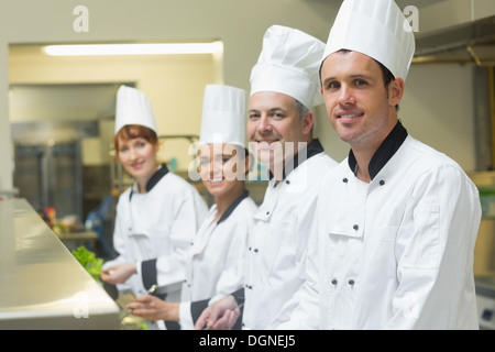 Four chefs working in a kitchen standing in a row Stock Photo