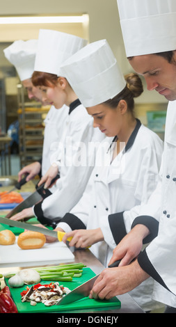 Chefs standing in a row cutting vegetables Stock Photo