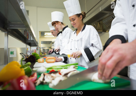 Four chefs preparing food at counter in a row Stock Photo