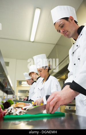 Four chefs preparing food at counter in a row Stock Photo