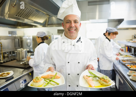 Mature head chef presenting proudly some dinner plates Stock Photo
