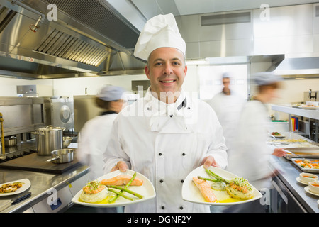Mature head chef presenting proudly two dinner plates Stock Photo