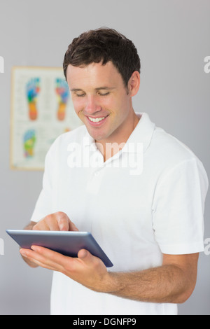 Handsome smiling physiotherapist using tablet Stock Photo
