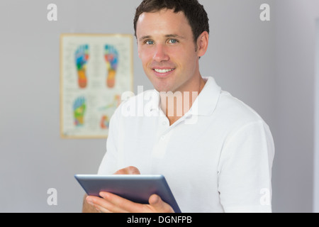 Handsome cheerful physiotherapist holding tablet Stock Photo