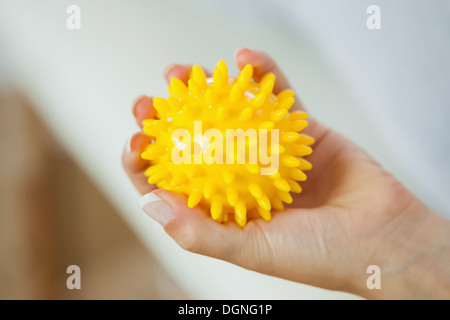 Close up of female left hand holding yellow massage ball Stock Photo