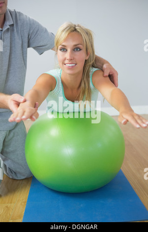 Physiotherapist holding patient doing exercise on exercise ball Stock Photo