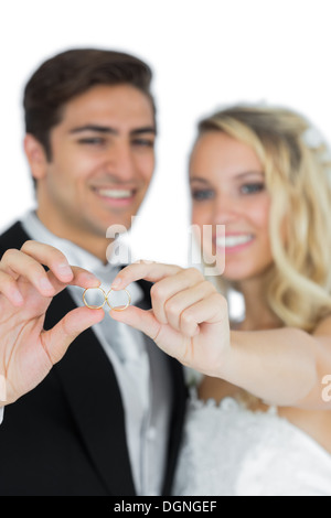 Smiling young married couple holding their wedding rings Stock Photo