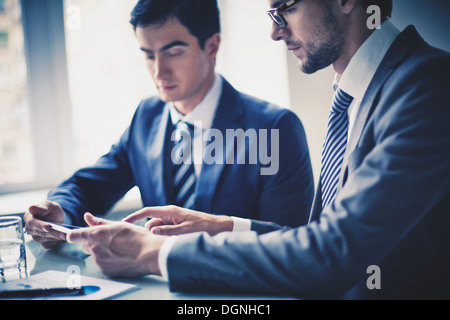Image of two young businessmen using touchpad at meeting Stock Photo