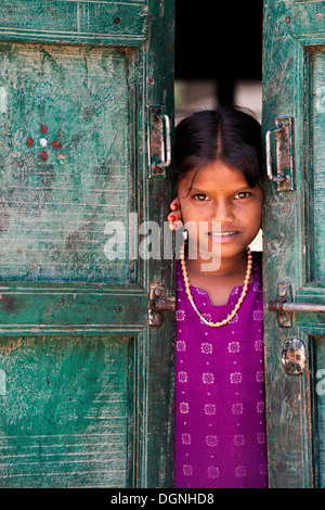 Rural Indian village girl standing in front of house doors. Andhra